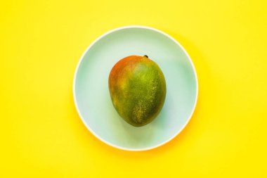 Mavi bir tabakta yatan mango. Düz Yat.
