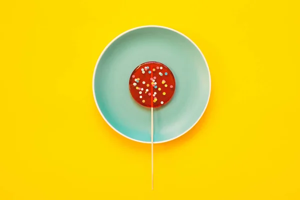 Sarı arka planda büyük kırmızı bir lolipop..