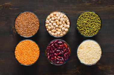 Farklı mısır gevrekleri ve baklagiller bir cam kasede siyah bir masada, düz bir şekilde yatıyordu.