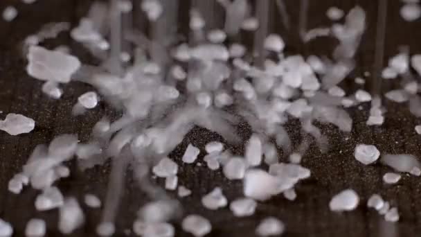 Crystals of white sea salt fall on the wooden table. — 비디오