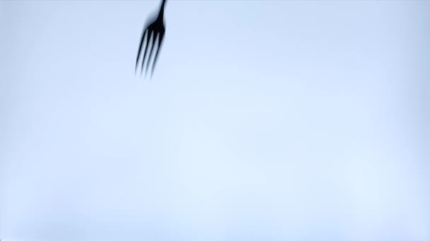 Silueta tenedor metálico y cuchara cayendo sobre la mesa sobre fondo blanco — Vídeos de Stock