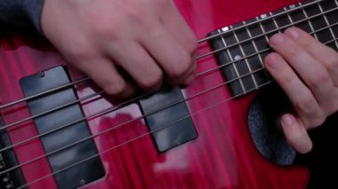 Kırmızı elektro gitar çalan bir adamın parmaklarının yakın çekimi..