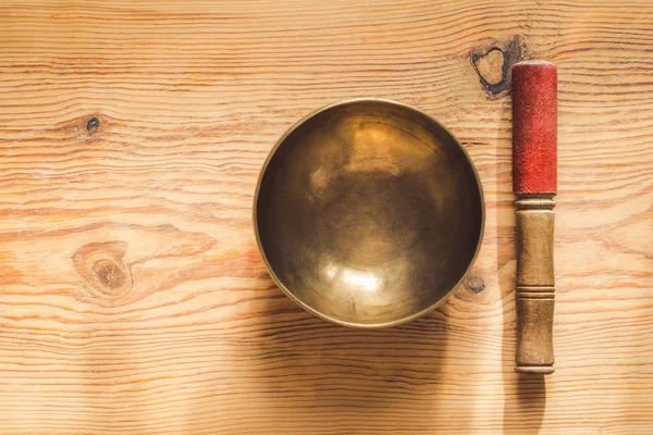 Θιβετιανό χάλκινο μπολ και ξύλινο ραβδί σε ξύλινο τραπέζι. — Φωτογραφία Αρχείου