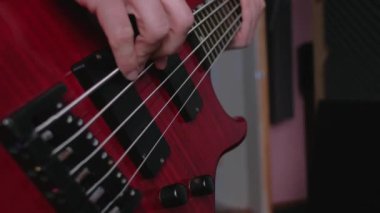 Kırmızı elektro gitar çalan bir adamın parmaklarının yakın çekimi..