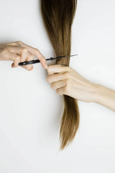 Жінка вирізає довге пряме волосся ножицями — стокове фото