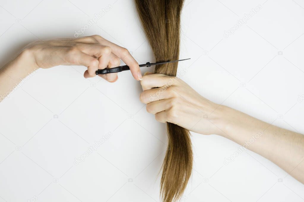 Upset woman cuts her long straight hair with scissors