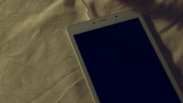 Frauenhand steckt weißes Ladekabel in digitales Tablet, das sich entlädt. — Stockvideo