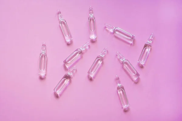 Pembe arka planda ilaç ampulleri. İlaç, tedavi..