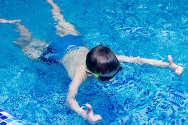 gözlüklü çocuk havuzunda yüzüyor