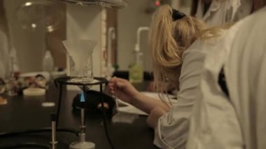 Kimya laboratuvarında not alan öğrencilerin yakın çekim görüntüleri.