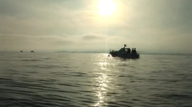 Gün batımında balık tutan adamlarla geniş açılı bir tekne görüntüsü.
