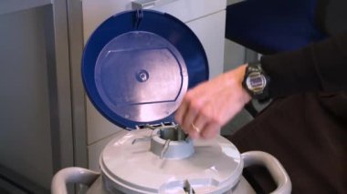 Laboratuvar teknisyeninin ellerinde sıvı nitrojen içinde numune tutan bir kabın içinden numune alan kişiye yaklaş..