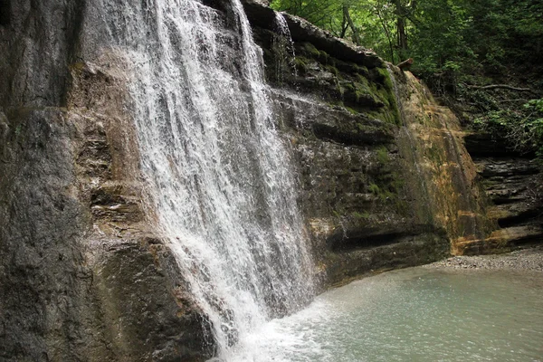 nehre düşen bir şelale ile kayalık dağ