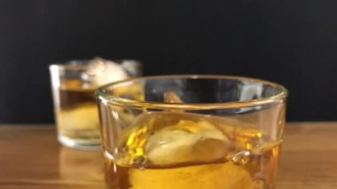 Bir parça buz, bir bardak viskinin içine düşer. Tahta bir masanın üzerinde durur..