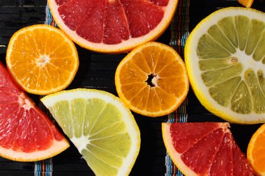 Koyu arkaplanda farklı renklerde narenciye dilimleri.