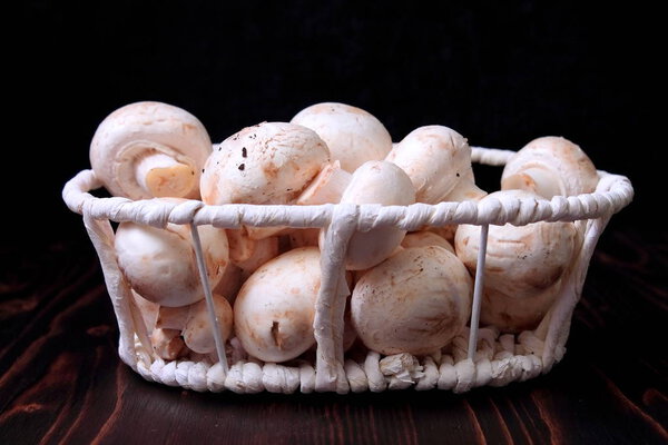 Свежие грибы шампанского в белой плетеной корзине
