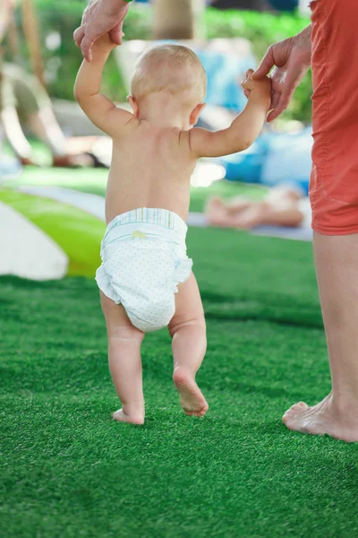 Small child in diapers is taking its first steps — Stock Photo, Image