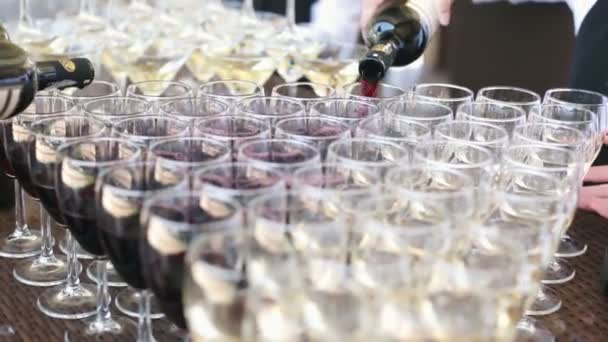 The waiter pours red wine in the rows of glasses at the festival — Stock Video