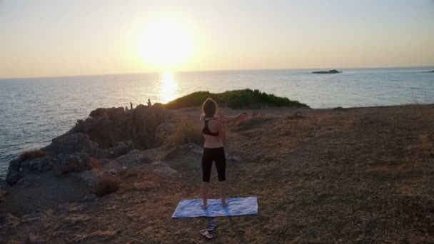 The girl trains at sunset on the seashore — Stock Video