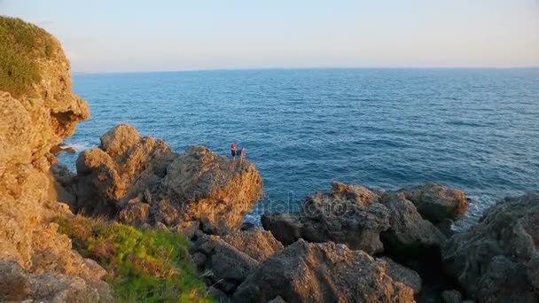 Twee jongens reiziger permanent op de rotsen van de kust — Stockvideo