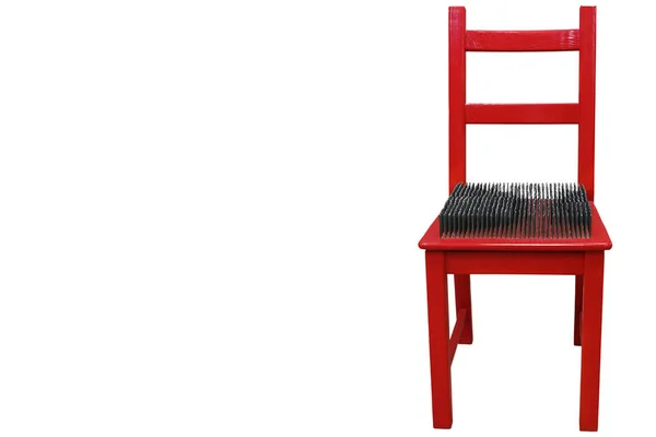 Красный стул с шипами на сиденье — стоковое фото