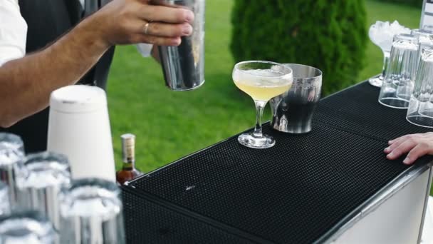 Der Barkeeper bereitet das Getränk mit Limette zu und gibt es dem Gast — Stockvideo