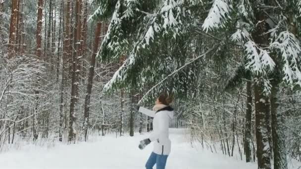 Счастливая девушка бежит в зимнем лесу — стоковое видео