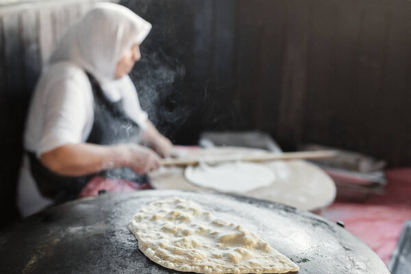 Granny chef cook Turkish pancake Gozleme on the stove