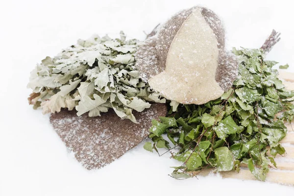 Birch broom and hat of felt on the snow — Stock Photo, Image