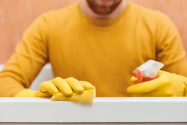 Homem limpa banheiro com esponja e produtos de limpeza — Fotografia de Stock