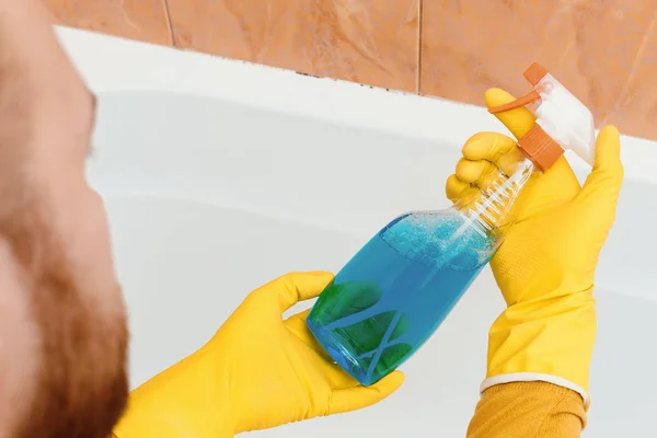 Мужчина держит моющее средство от плесени в ванной комнате — стоковое фото