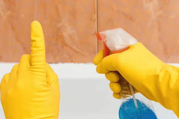 Hand in rubber gloves indicates mold in the bathroom