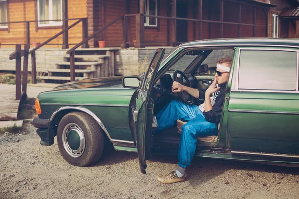 Chlap v devadesátých letech sedí za volantem auta kouří cigaretu Stock Fotografie