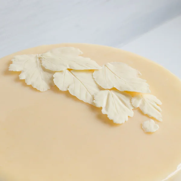 Blätter weißer Schokolade auf dem Kuchen mit einer glatten Glasur. — Stockfoto