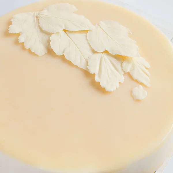 Blätter weißer Schokolade auf dem Kuchen mit einer glatten Glasur. — Stockfoto