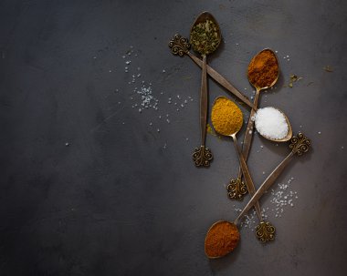 Parlak gri beton zemin üzerine vintage kaşık baharatlar. Minimalizm. Karanlık fotoğraf.