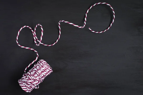 Christmas red white string on a black wooden background.