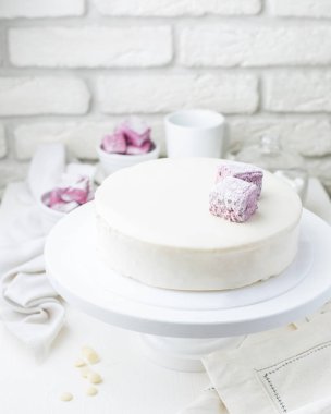 Bir kafede marshmallow ile kremsi beyaz mousse kek fotoğraf. Kesilmiş bir parça ile modern bir pasta. Açık renkli, beyaz tuğla duvar, hafif yemekler ve kek standı. Kahve evinin atmosferini. 