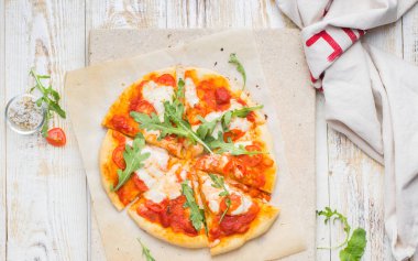 Napolice pizza domates, mozzarella peyniri, roka hafif bir taş ve ahşap bir arka plan ile. nefis.) Düz yatıyordu, en iyi görünüm. Elleri ile gıda fotoğraf.