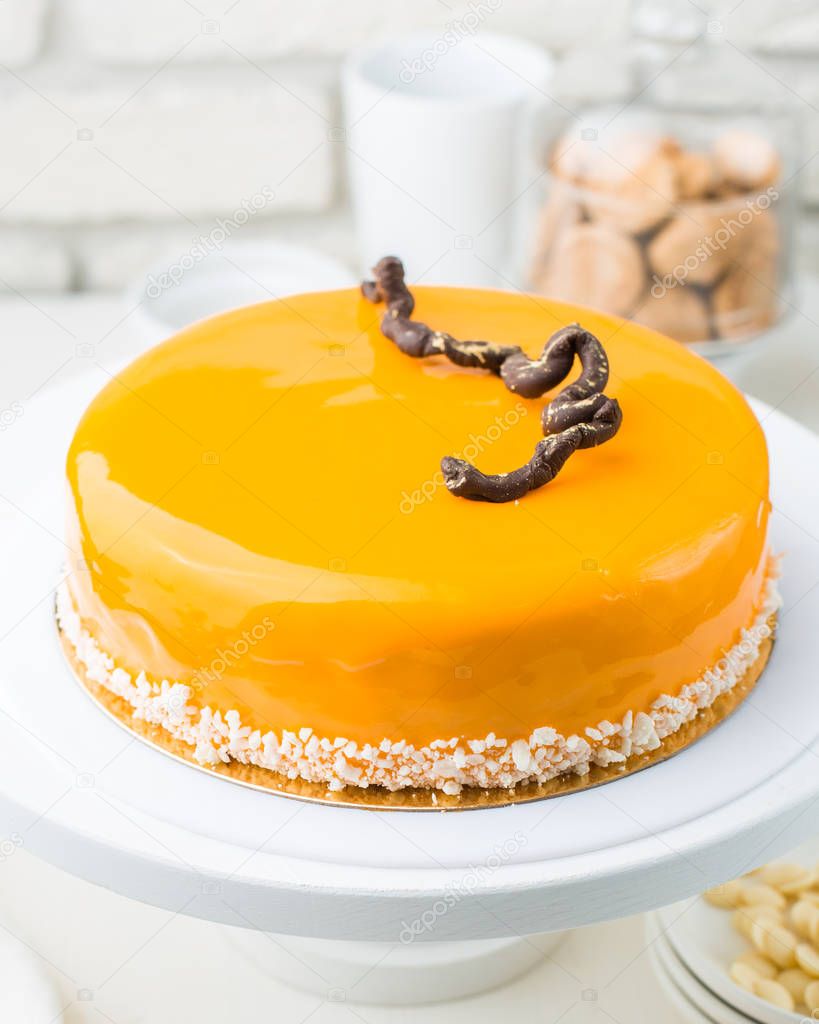 Photo of a carrot honey mousse cake in a cafe. A modern cake with a cut piece. Light background, white brick wall, light dishes and cake stand. The atmosphere of the coffee house. sweet photo