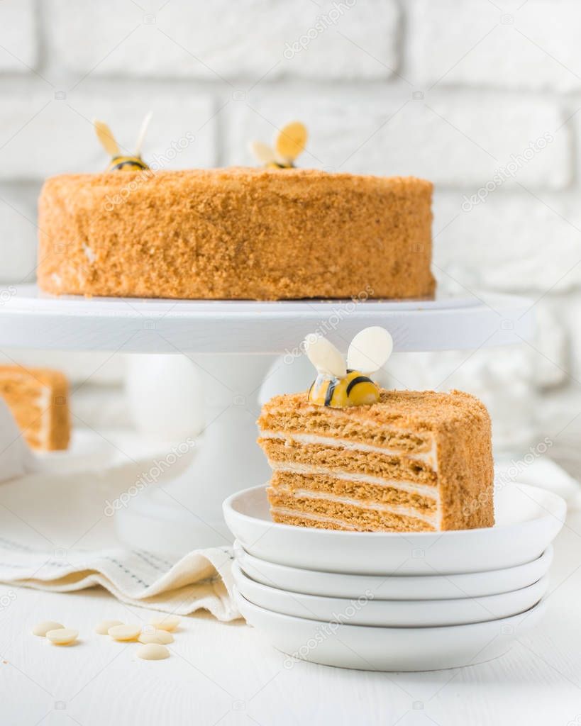 Photo of a carrot honey cake with bees in a cafe. A modern cake with a cut piece. Light background, white brick wall, light dishes and cake stand. The atmosphere of the coffee house. sweet photo