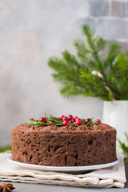 Geleneksel Noel İngilizce puding (meyveli kek) biberiye ve kızılcık hafif beton bir arka plan üzerinde beyaz tabakta. Noel dekor tablo.  