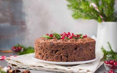 Geleneksel Noel İngilizce puding (meyveli kek) biberiye ve kızılcık hafif beton bir arka plan üzerinde beyaz tabakta. Noel dekor tablo.  