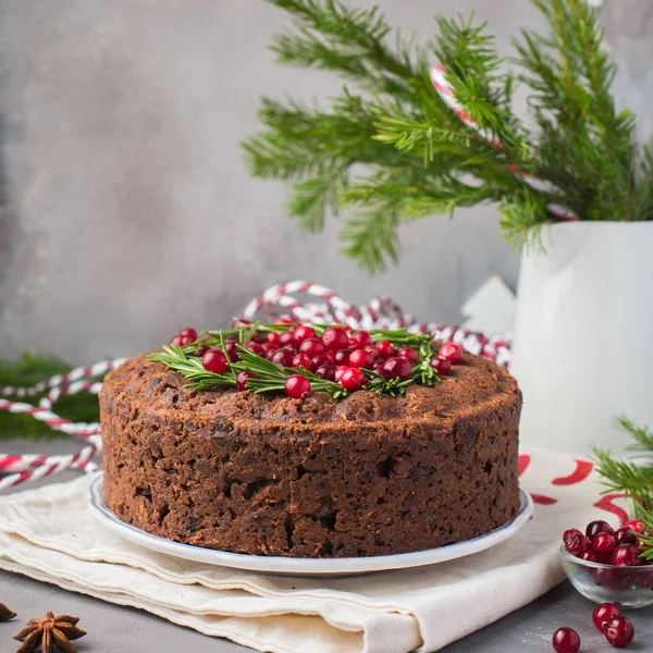 Geleneksel Noel İngilizce puding (meyveli kek) biberiye ve kızılcık hafif beton bir arka plan üzerinde beyaz tabakta. Noel dekor tablo.  