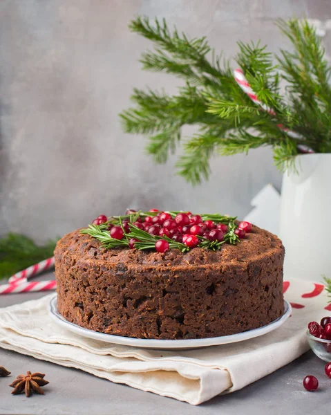 Geleneksel Noel İngilizce puding (meyveli kek) biberiye ve kızılcık hafif beton bir arka plan üzerinde beyaz tabakta. Noel dekor tablo.  