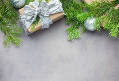 Noel arka planda gri-mavi renkler kraft kağıt sarılmış hediyeler, şeritler, cam Noel ağacı topları ve xmas ağacı ile. Düz yatıyordu, en iyi görünümü