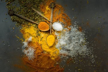Bright vintage kaşık - safran, tuz, kekik, biberiye, gri beton zemin üzerine kırmızı biber biber baharat. Karanlık gıda fotoğraf.
