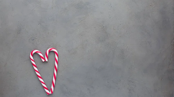 Heart of two candy canes on the gray concrete background. Beautiful background.Flat lay, top view