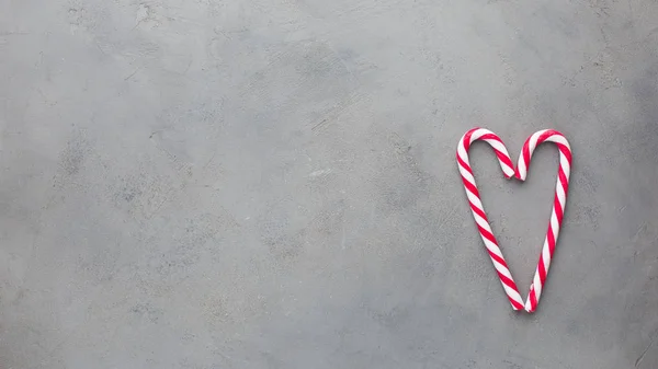 Heart of two candy canes on the gray concrete background. Beautiful background.Flat lay, top view