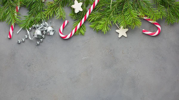 Red-white candy canes on the gray concrete background with Christmas tree. Beautiful Christmas background.Flat lay, top view